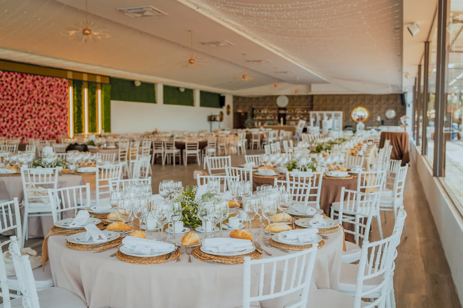 Salón de banquete montado con mesas redondas, iluminación de estrellas y muro floral