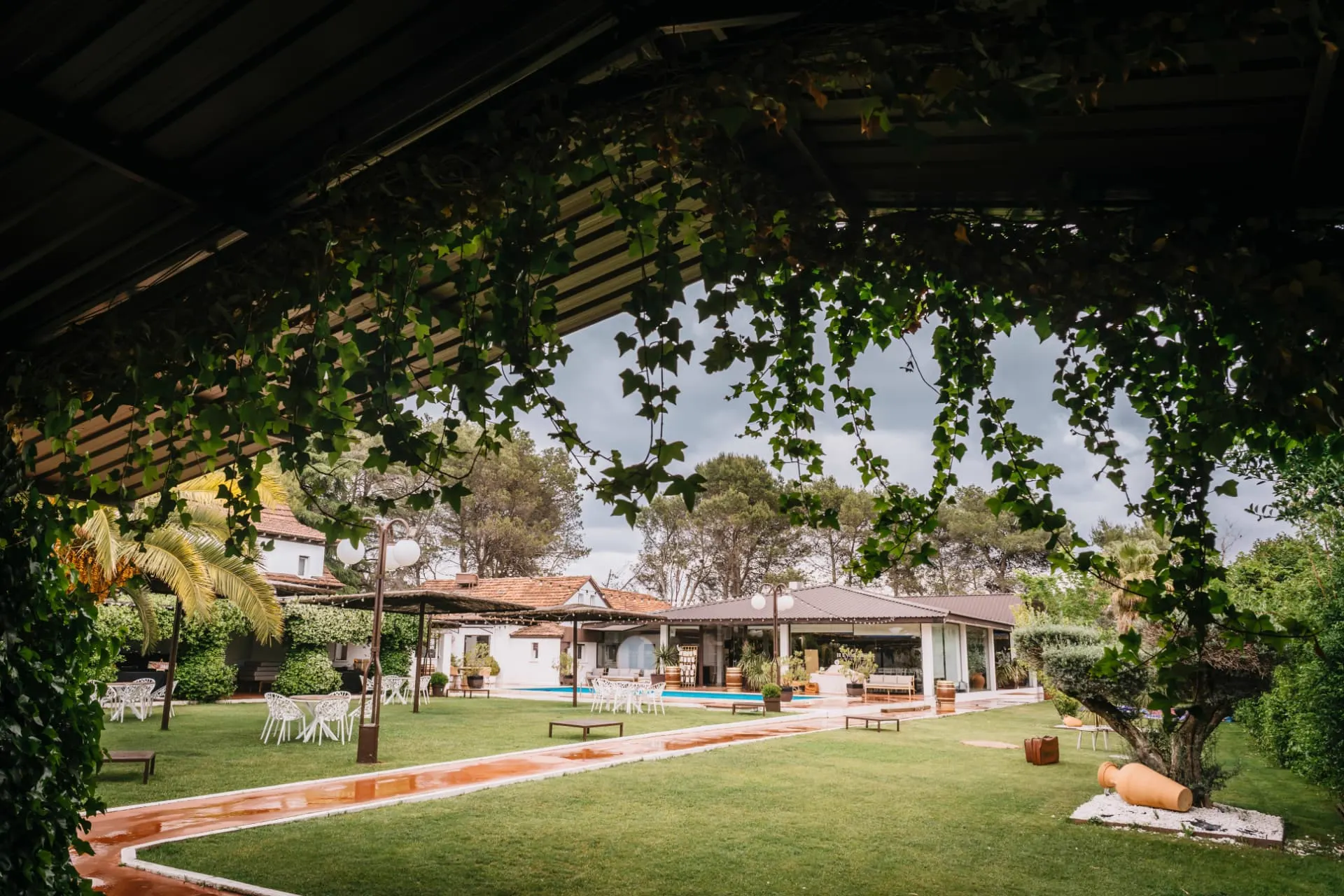 Jardín de finca con piscina y pérgola cubierta de hiedra