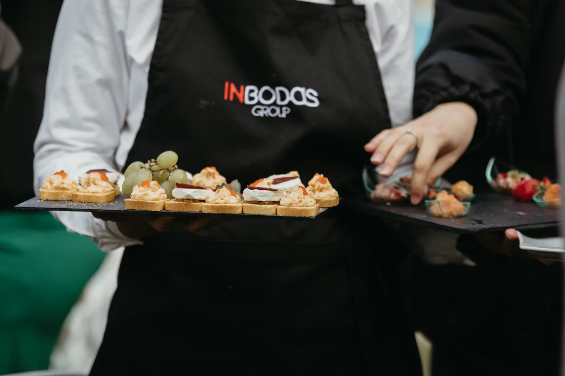 Camarero de InBodas sirviendo una bandeja de aperitivos durante un cóctel