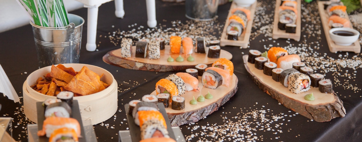 Mesa con rollitos de sushi sobre platos de madera hechos con troncos
